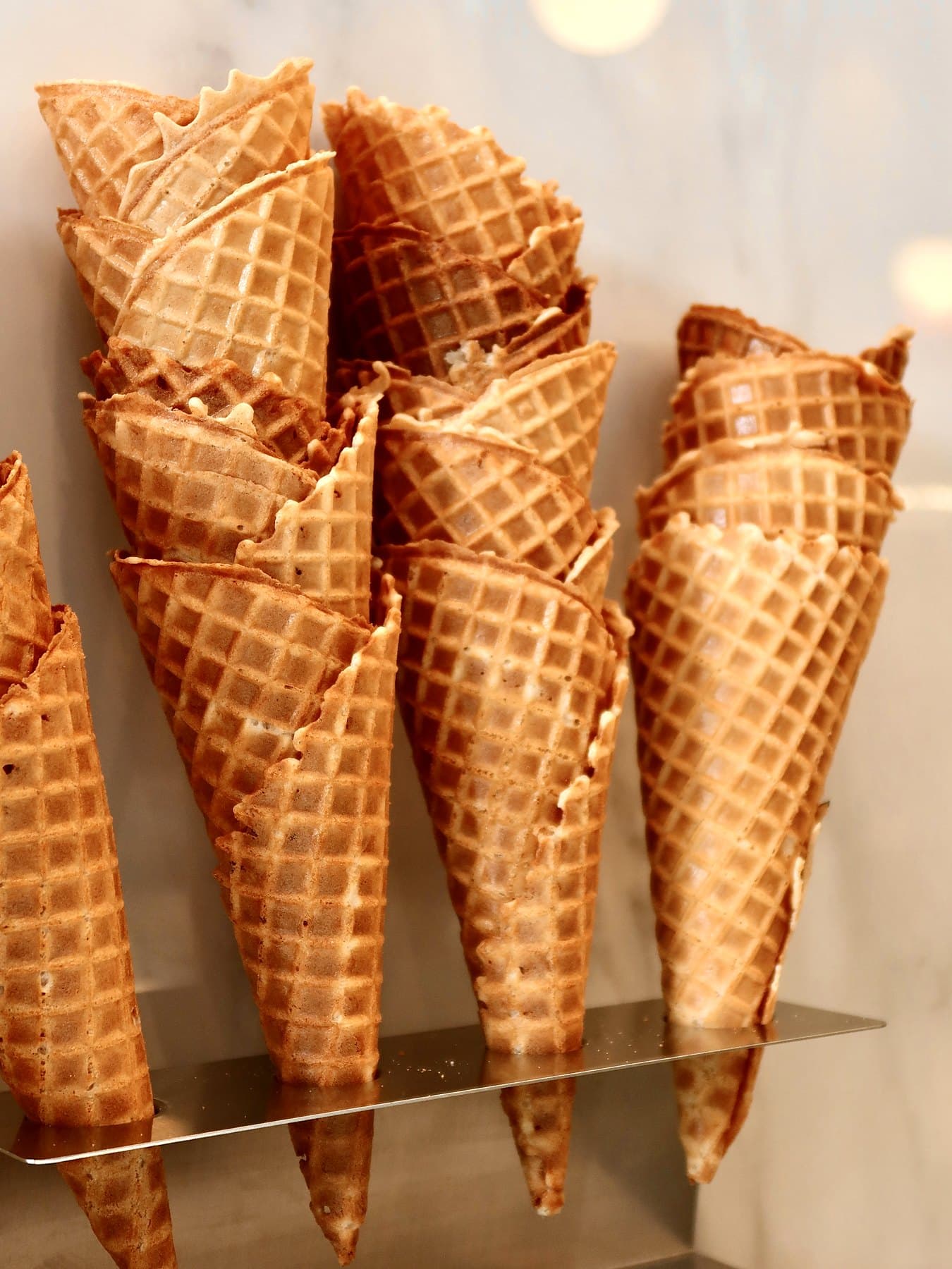 A stand of freshly pressed waffle cones against white marble
