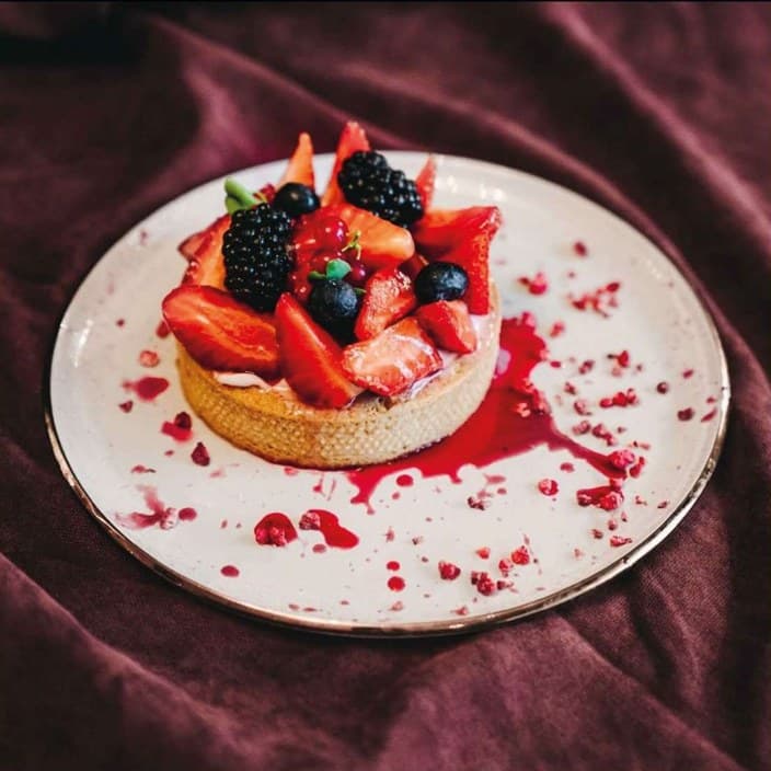 Tartlet with strawberries, blueberries and raspberry coulis on a velvet backdrop