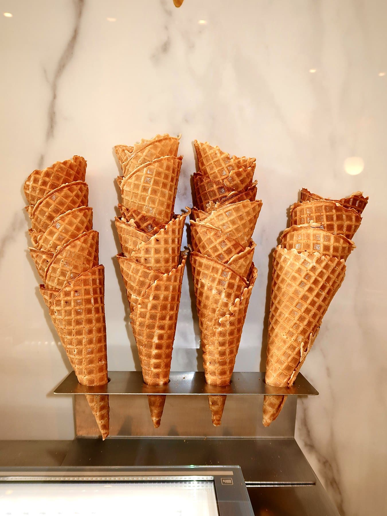 Fresh waffle cones standing in a rack on the marble counter